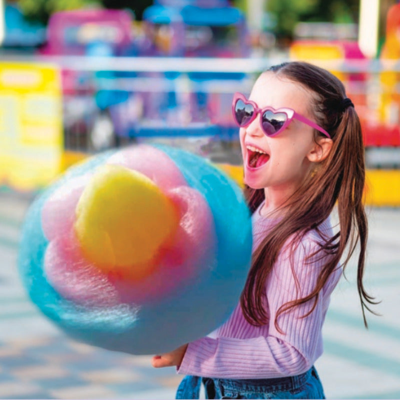 young girl with a large smile, holding a large tri-color cotton candy flower made by a Sweet Robo Model VX Cotton Candy Vending Machine