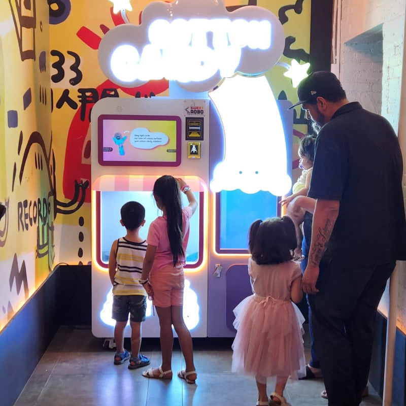 a family waits for their cotton candy to be made by the Sweet Robo Model VX Cotton Candy vending machine