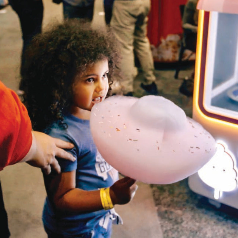picture of a young child eating cotton candy with sprinkles made by a Sweet Robo Model VX Cotton Candy Vending Machine