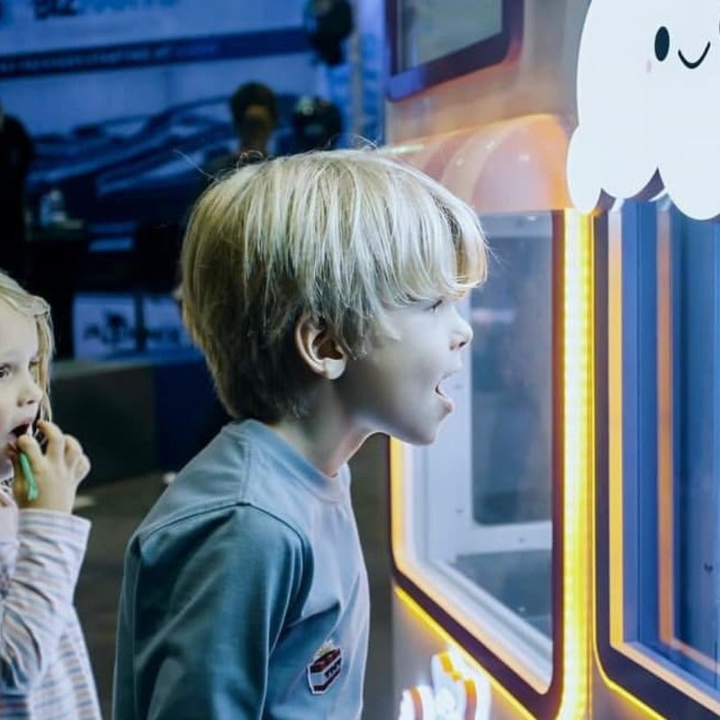 two young children watch in wonder as cotton candy is being made by the Sweet Robo Model VX Cotton Candy Vending Machine