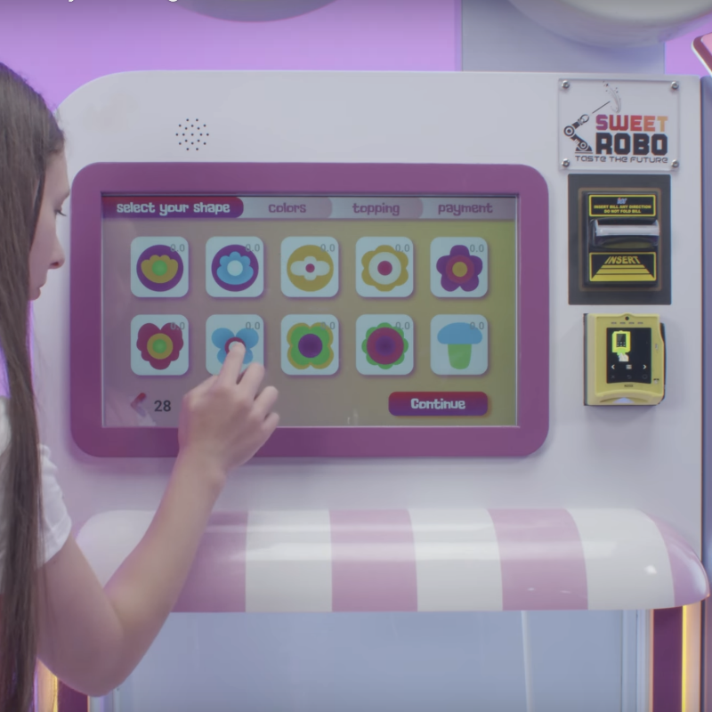 Front view of a young girl using the touchscreen control panel of a Sweet Robo Model VX Cotton Candy Vending Machine
