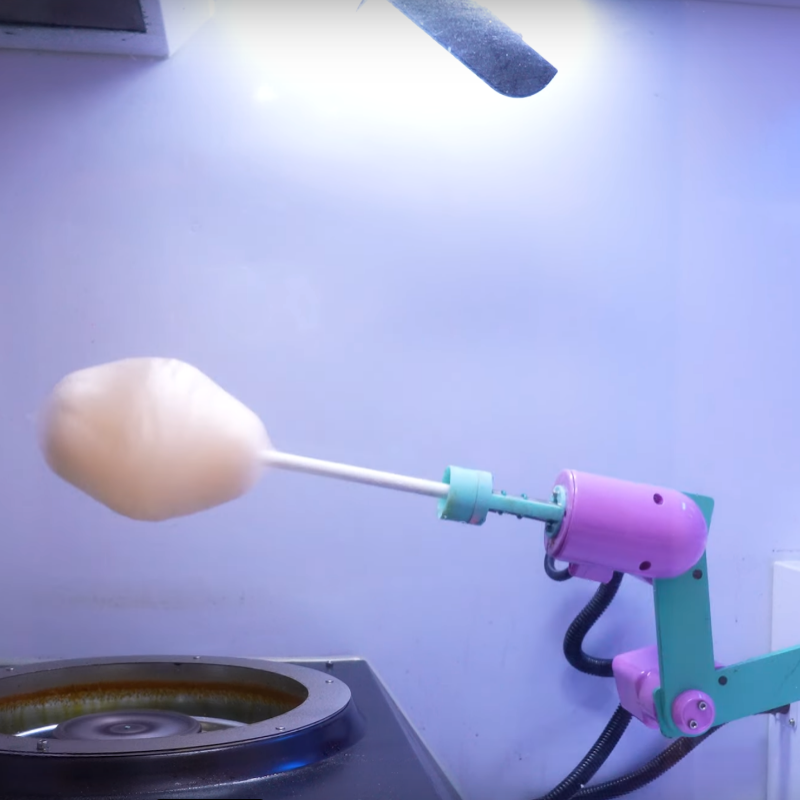picture of brightly colored robot arm with cotton candy on it, inside a Sweet Robo Model VX Cotton Candy Vending Machine